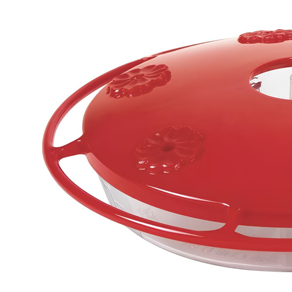 Close-up of a red plastic feeder lid with embossed floral details and a clear container visible underneath photographed on a white background
perch & weather